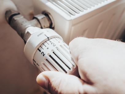 Main d'homme baissant le thermostat de son chauffage radiateur