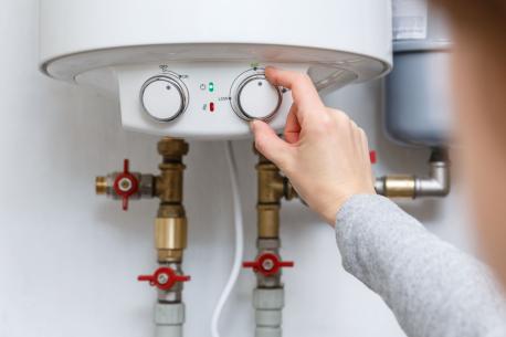 Main de femme réglant le thermostat de son chauffe-eau