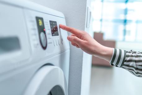 Main de femme choisissant un programme sur son lave-linge